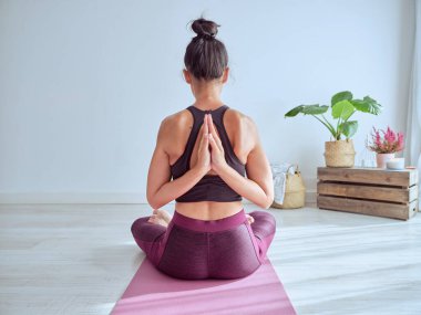 Meditasyon sırasında Padmasana poziyonunda arkanızda dua eden elleri olan kimliği belirsiz bir kadın var.