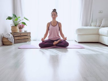 Uzun boylu, gözleri kapalı, sağlıklı bir yaşam tarzı olan, Lotus pozunda yoga yapan, elleri gyan mudra ile gerilmiş bir kadın.