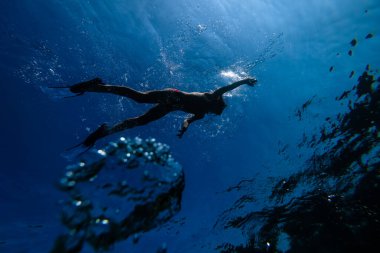 Derin mavi deniz suyunda yüzen yüzgeçli ve şnorkel maskeli tanımlanamayan erkek dalgıcın tüm vücudunun altından.
