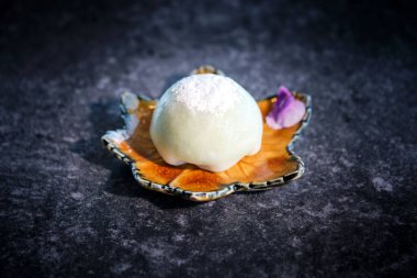 Ev yapımı iştah açıcı Japon mochi pirinç keki akçaağaç yaprağı tabağında servis edilir ve üzerine şeker tozu serpiştirilir.