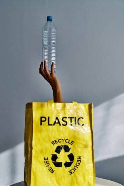 Tanımlanamayan bir kadın torbadan boş plastik şişeyle geri dönüşüm için çöp topluyor.