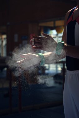 Tanınmayan sporcu spor jimnastiği egzersizleri yapmak için eline magnezyum tutuşturarak kendini hazırlıyor..