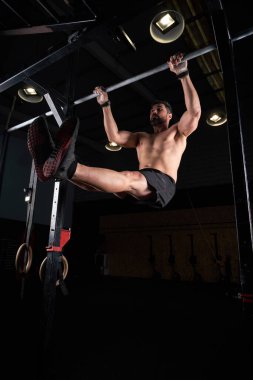 Karanlık spor kulübünde çıplak gövde bükücü bacakları olan sporcunun düşük açısı.