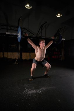 Spor salonunda antrenman yaparken ağırlık kaldıran profesyonel kaslı erkek sporcu vücudu.