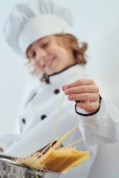 在准备糕点的时候 穿着厨师制服 头戴帽子 把意大利面棒放在碗里 非常可爱 — 图库照片