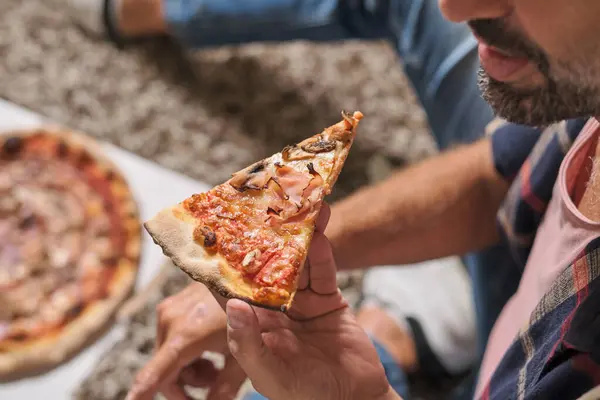 ハムスライスパーティーで美味しいピザを食べる高角度クロップ匿名男性 — ストック写真