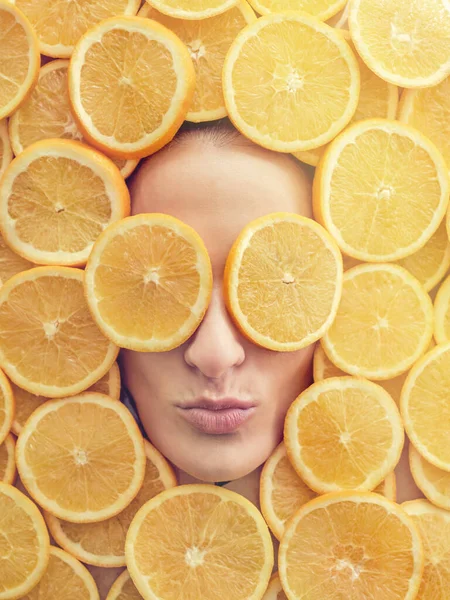 Top view of anonymous woman pouting lips with slices of fresh oranges on eyes