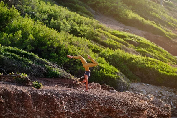 スポーツウェア姿の若い女性アスリートの横顔阿度無香Vrikshasanaは山の斜面でヨガをしながら足を離れてポーズ — ストック写真
