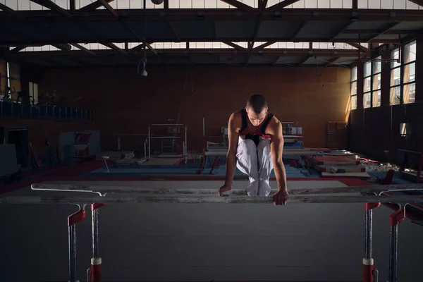 若い男性体操選手が平行装置で練習を行う — ストック写真