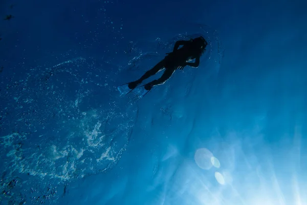 夏の青い海水に浮かぶシュノーケリングマスクでウェットスーツとフリッパーで完全な体の下から — ストック写真