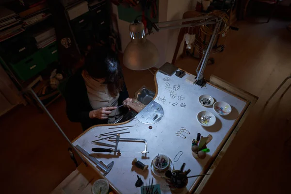 Yüksek Açılı Isimsiz Kadın Kuyumcu Dosyasıyla Metali Düzleştiriyor Masada Lamba — Stok fotoğraf