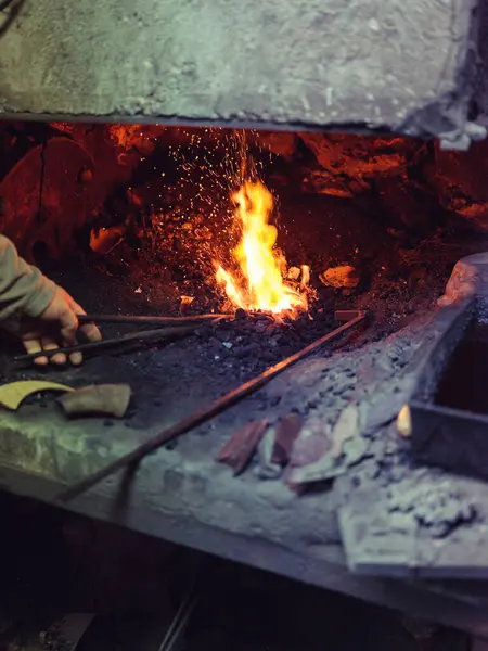 伝統的なスミスでの作業中に炉で舌で金属を加熱する匿名の男性ブラックスミスを作る — ストック写真