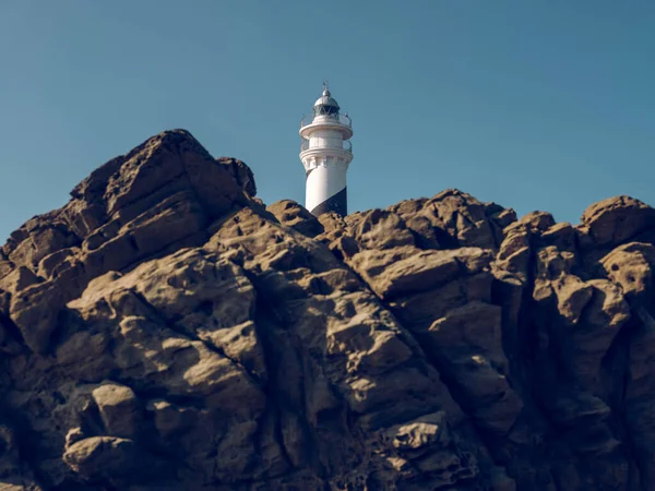Beyaz Deniz Fenerinin Resimli Manzarasının Altından Dağlık Arazide Bulutsuz Mavi — Stok fotoğraf
