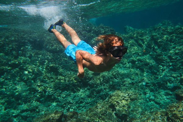 Полное тело ребенка плавает глубоко возле коралловых рифов на дне моря наслаждаясь летним днем