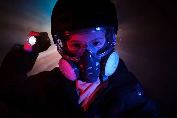 Robber in protective respirator looking at camera with shining flashlight while standing in dark mist with neon lights and committing crime