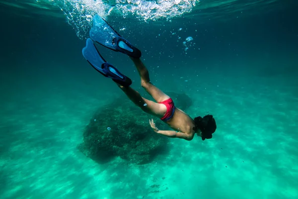 シュノーケリングマスクとスリッパで匿名の若い男性ダイバーの完全な体水中で泳ぎ 海底のサンゴ礁と生態系を探索する — ストック写真