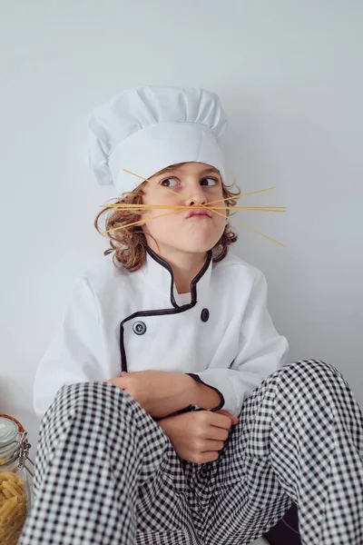 Roztomilý Preteen Chlapec Kostýmu Šéfkuchaře Čepice Grimacing Pomocí Špagety Tyčinky — Stock fotografie