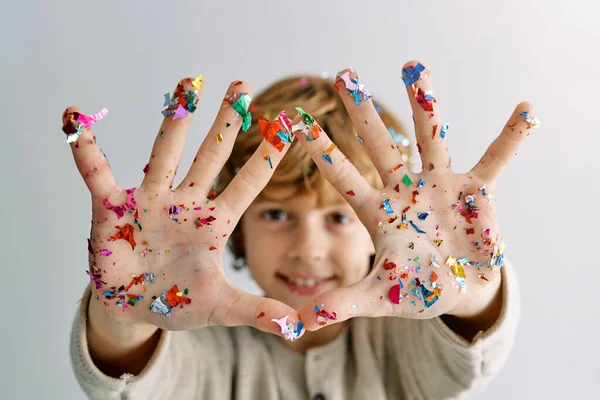 Rapaz Positivo Mostrando Mãos Com Confetes Multicoloridos Enquanto Estava Contra — Fotografia de Stock