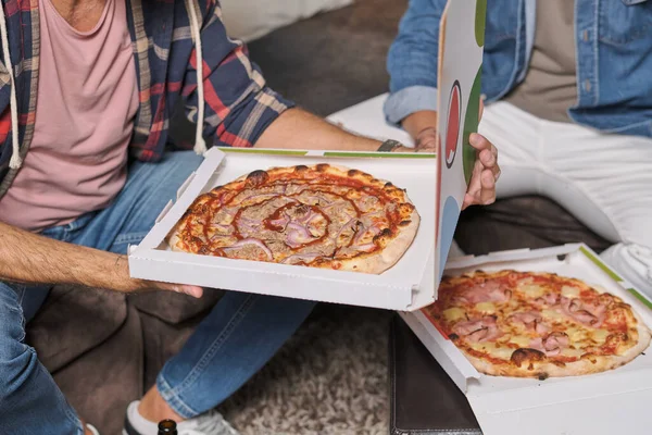 カジュアルな服で匿名の男性のハイアングルは 自宅の箱に全体のおいしいピザと一緒に座っています — ストック写真
