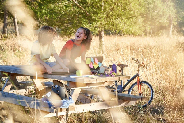 Full Length Laughing Girl Boy Sitting Wooden Picnic Table Browsing — Stock Photo, Image