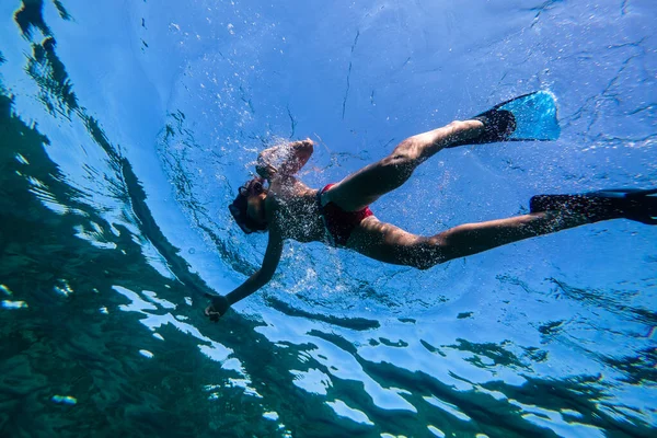 フィンとシュノーケリングマスクで透明な青い海水の下で泳ぐ完全なボディの下から — ストック写真