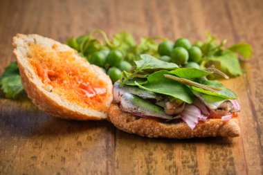 Yarı açık geleneksel hasat sandviçi sardalya, et ve farklı sebzelerle ahşap bir yüzeyde biraz da asma yaprak. Kanarya Adalarının Gastronomisi
