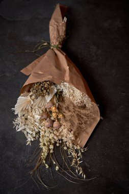 Kurumuş çiçeklerin el sanatları kağıdına sarılmış ve siyah arka plana yerleştirilmiş üst görünümü