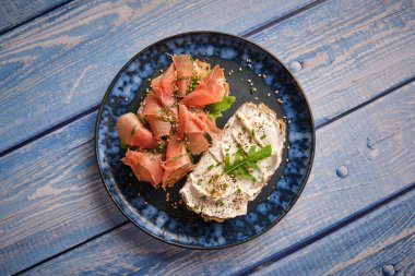 Ahşap masada servis edilen jamon dilimleri ve krem peynirli leziz bruschetta 'dan.