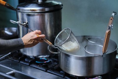 Stock photo of unrecognized chef cooking noodles in the kitchen of japanese restaurant. clipart