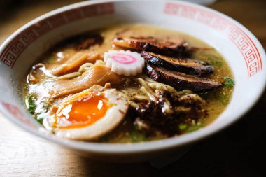 Narutomaki 'li lezzetli ramen ve seramik kasede servis edilen et ve ahşap masaya konmuş.