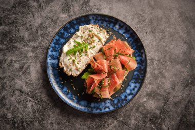 Ahşap masada servis edilen jamon dilimleri ve krem peynirli leziz bruschetta 'dan.