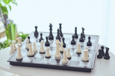 Masadaki satranç tahtasına yerleştirilmiş beyaz ve siyah taşlardan oluşan yüksek açılı bir set.