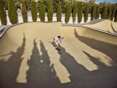 Güneşli bir günde kaykay parkında uzun kaykay kullanan bir çocuktan.