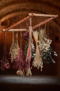 Kurumuş çiçeklerin buketlere yerleştirilmiş yaratıcı bileşimi ve bulanık arka plana karşı ahşap çerçevede asılı.