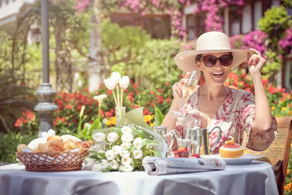幸福女人戴着太阳镜在花园里喝一杯香槟的照片 — 图库照片