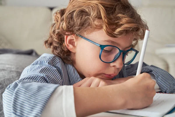 Günlük Giysiler Gözlükler Içinde Konsantre Olmuş Çocuk Aşağı Bakarken Ödevlerini — Stok fotoğraf