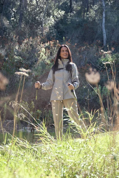 西班牙女性徒步旅行者心满意足 在大自然中远足时 她站在青翠的草地上仰视着远足的杆子 — 图库照片