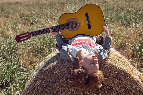 ハイロールで晴れた日を楽しむアコースティックギターとリラックスした少年と田舎の喜びから目を閉じる — ストック写真