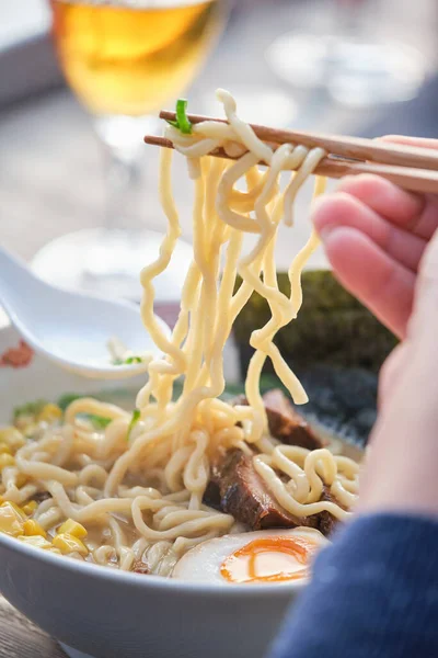 Stock photo of unrecognized person enjoying noodles soup in japanese restaurant.