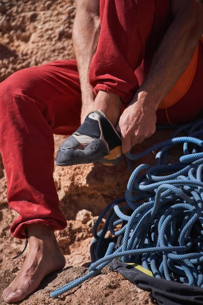 Bezimienny Alpinista Zakładający Buty Wspinaczkowe Siedząc Szorstkiej Skalistej Ziemi Pobliżu — Zdjęcie stockowe