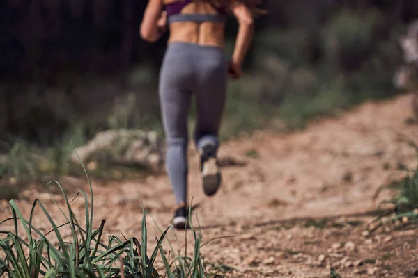 阳光明媚的清晨 穿着运动服和运动鞋在崎岖小径上跑步在森林里进行户外运动的无名女运动员的倒影 — 图库照片