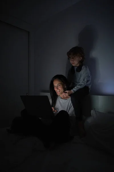 Menino Abraçando Mulher Sorridente Enquanto Sentado Cama Assistindo Vídeo Laptop — Fotografia de Stock