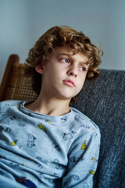 Spokojny Chłopiec Kręconymi Włosami Brązowymi Oczami Siedzący Kanapie Odwracający Wzrok — Zdjęcie stockowe