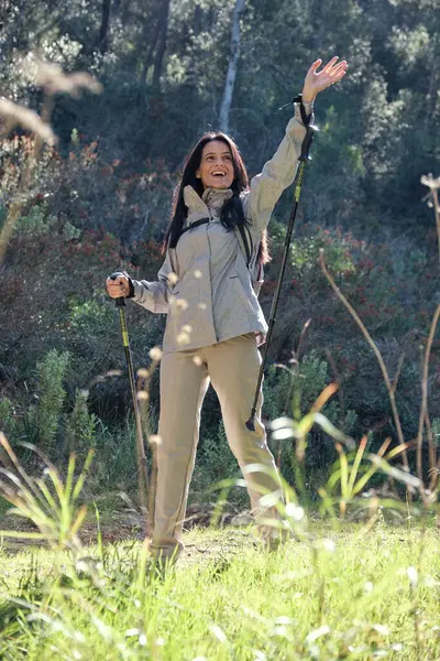 夏日徒步游览大自然时 站在草地上 手拿着手杖站在草地上的积极的西班牙裔女性 — 图库照片