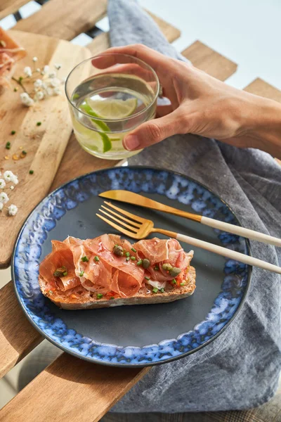 Crop Anonymous Person Sitting Wooden Table Delicious Prosciutto Toast Served — Stock Photo, Image