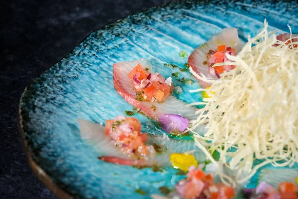 Rendelenmiş daikon turplu iştah açıcı Asya yemekleri ton balığı ve taze kesilmiş sebzelere karşı yuvarlak tabakta servis edilir.