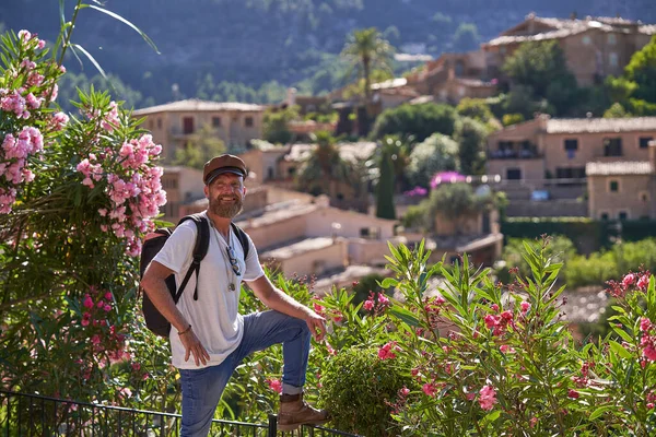 Turista Masculino Sonriente Traje Elegante Con Mochila Cerca Arbustos Florecientes — Foto de Stock