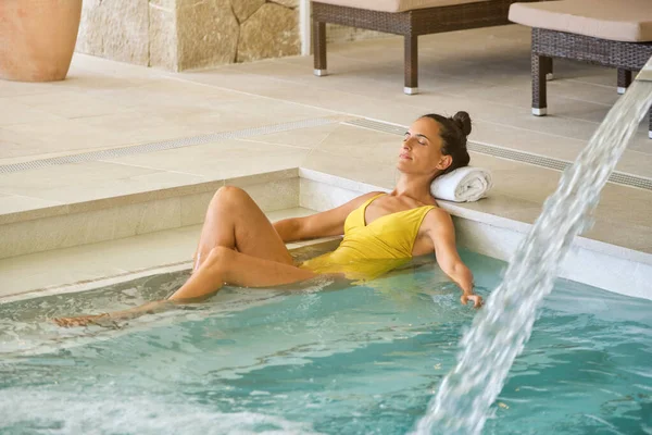 夏休みをリゾートで過ごす間 目を閉じてプールの階段に横たわっている黄色の水着の大人の女性の全身 — ストック写真