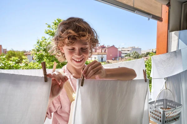 Uśmiechnięty Dzieciak Kręconymi Włosami Pomocą Szpilki Prania Powiesić Kolejce Balkonie — Zdjęcie stockowe