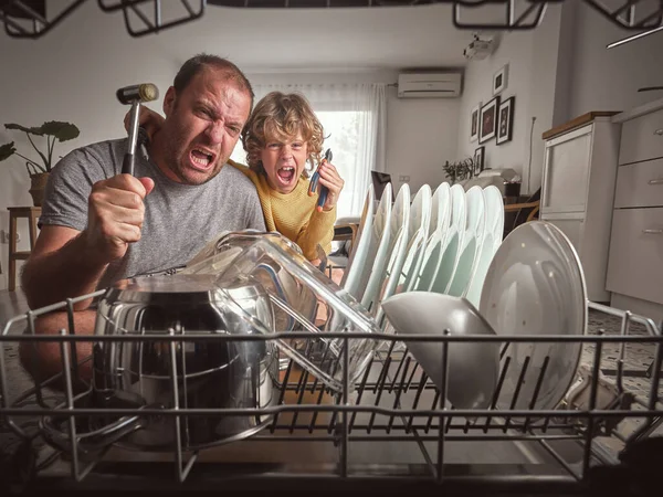 Profesyonel çekiçli öfkeli bir baba ve oğlu birlikte ev işi yaparken mutfakta bulaşık makinesinin yanında oturuyor.
